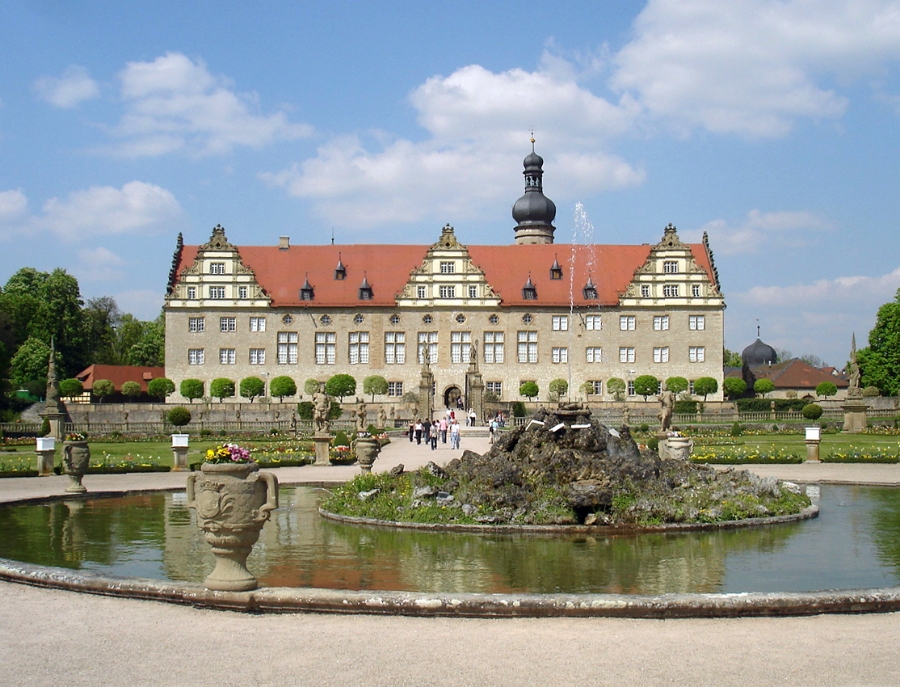 Exploring the German Castle Road: A Complete Guide 6 Weikersheim Palace, a grand building featuring an ornate fountain in the foreground, surrounded by lush greenery.