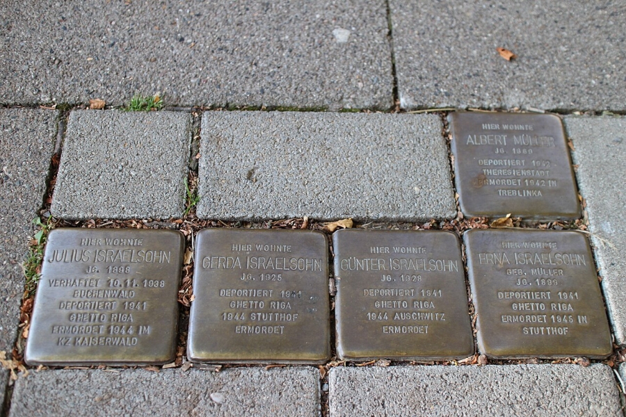 Four bronze Stolpersteine plaques embedded in the ground along Wilhelmstraße, commemorating victims of the Holocaust.
