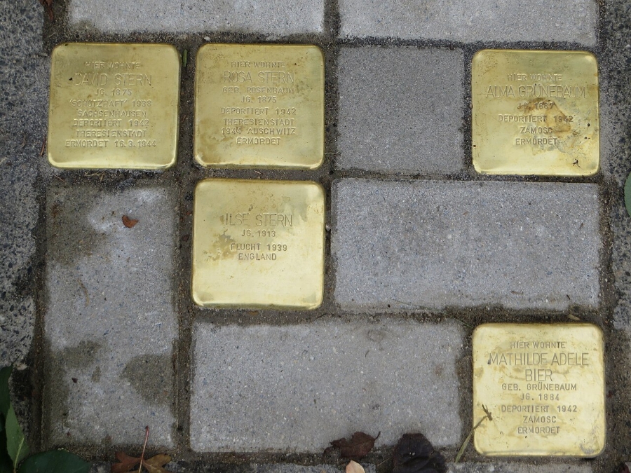 Close-up view of six gold memorial plaques on the sidewalk, honoring Holocaust victims at Gerberstraße.