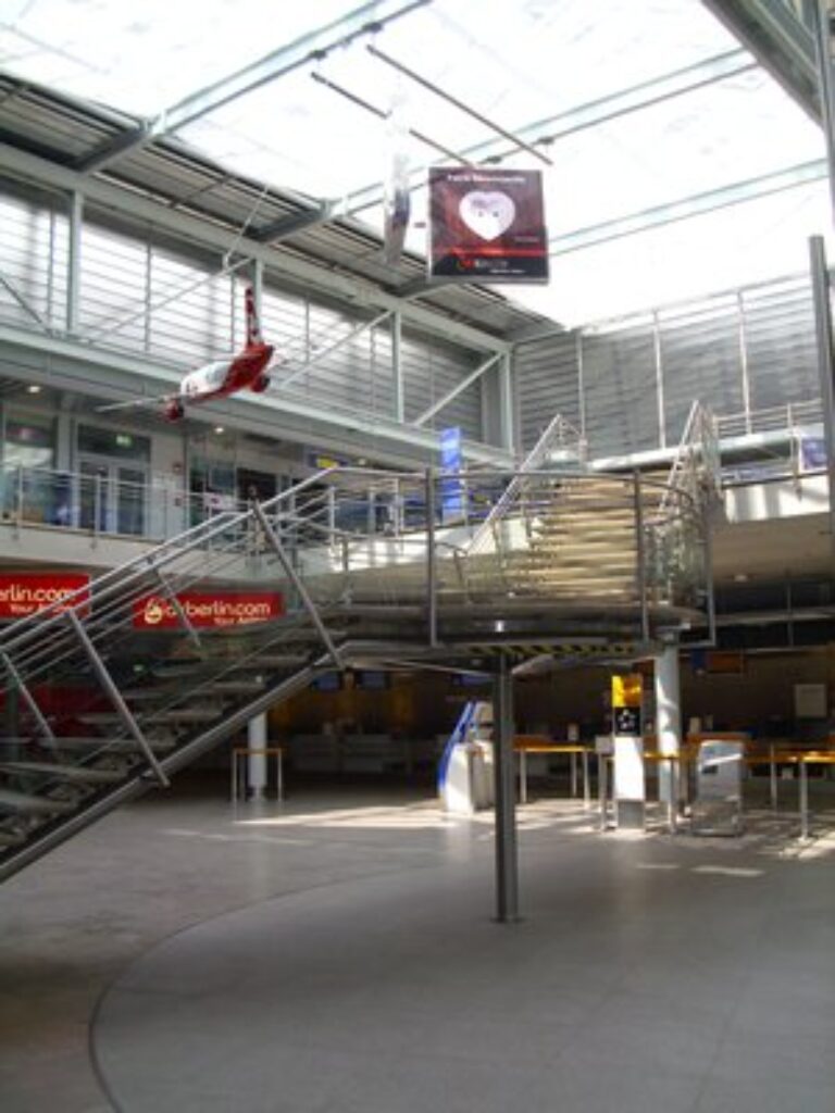 Nuremberg Airport 15 Interior view of Nuremberg Airport featuring a large metal staircase leading to upper levels.