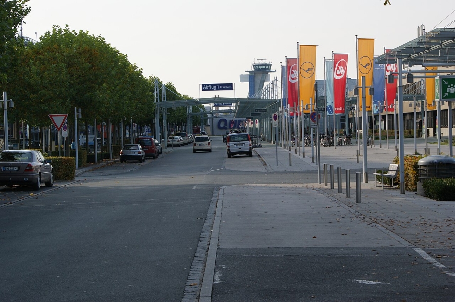 Nuremberg Airport 5 Nuremberg Airport drop-off zone featuring a crowded street filled with vehicles and various flags displayed prominently.