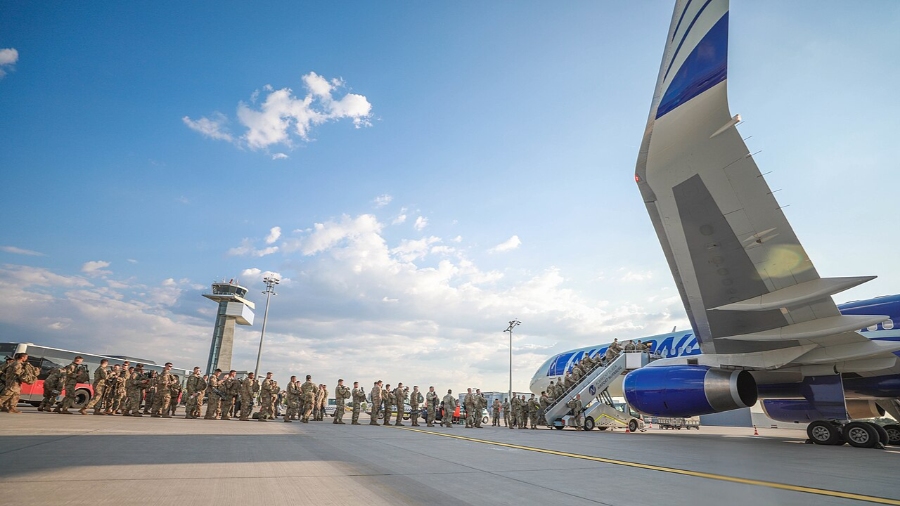 Soldiers gather around an aircraft at Nuremberg Airport, Germany, highlighting military operations and air travel.